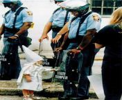 A Ku Klux Klan child and a black State Trooper meet each other, at a Klan rally protest in Gainesville, GA (1992). Innocence is mixed with hate. The toddler approached the trooper, who was holding his riot shield on the ground. Seeing his reflection, thefrom klan epizoda