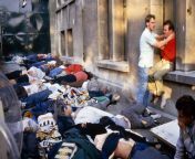 Heysel Stadium disaster, Belgium, May 29th, 1985. Human crush resulting in 39 deaths. A man comforts his friend next to dead bodies that have been laid haphazardly on the ground outside the stadium. The downdraught from police and medical helicopters hasfrom badamb stadium mod